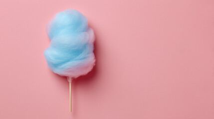 Top view of a fluffy blue cotton candy on a stick placed on a pastel pink background — a playful and nostalgic treat with space for text.

