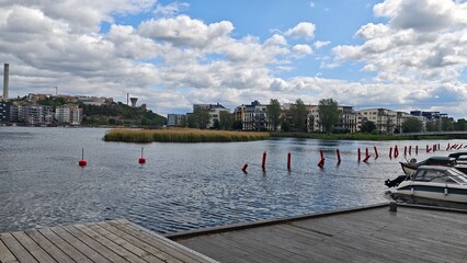 Modern waterfront buildings and moored boats along a calm urban canal under a cloudy sky