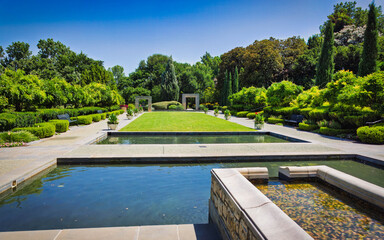 A large, serene garden with a pond and a fountain