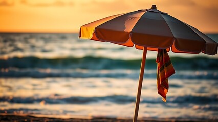 A beach umbrella with a colorful towel, basking in the golden light of sunset by the ocean.