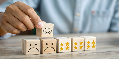 Hand placing happy face wooden block on row of blocks