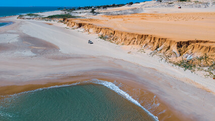 On a sunny day, a buggy with tourists riding on the white sand of Canoa Quebrada beach. Brazil.