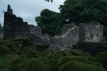 Ruins of an ancient stone structure nestled among lush greenery at dusk