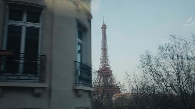 Eiffel tower emerging from parisian buildings during train journey