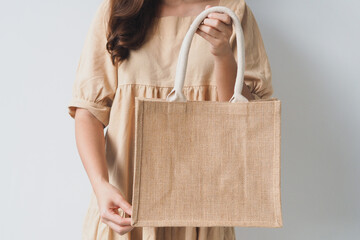 Woman holding  jute bag or sack bag on white background. Reusable shopping bag. Natural material. Zero waste. Plastic free. Eco friendly concept.