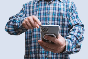 Man in a plaid shirt holding smartphone with blank screen on light background. Portable mobile technology concept.