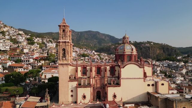 Aerial shot pulling back from Santa Prisca church showing white hillside homes in Taxco, Guerrero, Mexico