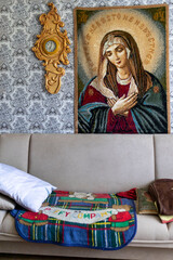 Fototapeta premium Dubna, Moscow region, Prislon village, July 20, 2025, Homey Sacred Space: Patterned Wallpaper, Folk Art Virgin Mary and Comfortable Sofa