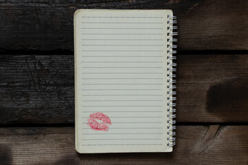 An open notebook with lines on a spiral lies on a wooden table, at the bottom of the page there is...