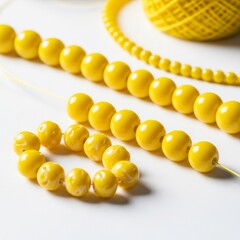 Fototapeta premium yellow glass beads and string laid out for jewelry making on a solid white background, crafting resource image