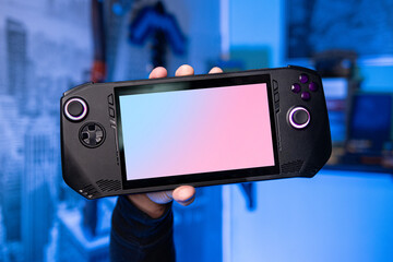 A hand holding a portable gaming console. Portable video game console. Handheld video game console. Portable console © Luka