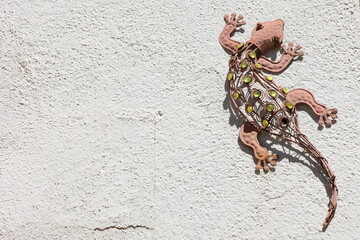 Lizard steel sculpture on textured wall background with copy space