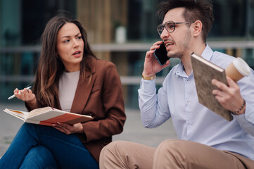 Businessman having phone call and ignoring colleague trying to talk to him