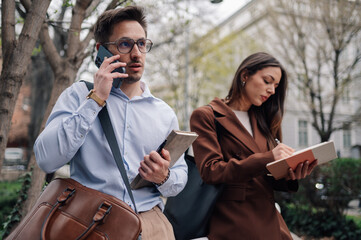 Businesspeople walking and talking on phone in urban setting