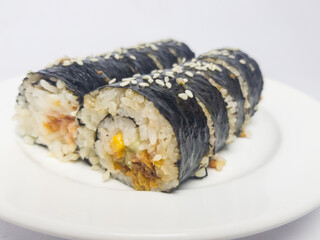 Sushi rolls filled with rice, seafood, and vegetables, wrapped in seaweed and sprinkled with sesame...