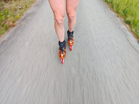 Legs in inline skates boots are moving on asphalt road