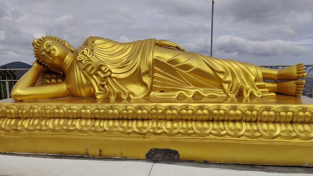 A reclining Buddha gold plated with Cloudy sky.