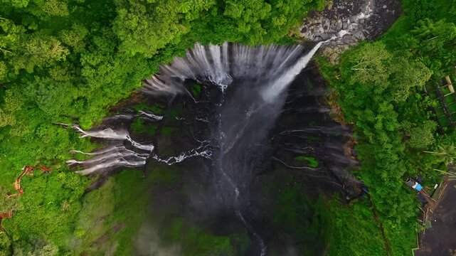 Aerial drone video of  Tumpak Sewu Waterfall in the tropical forest of East Java, Indonesia, drone flying above the waterfall. 


