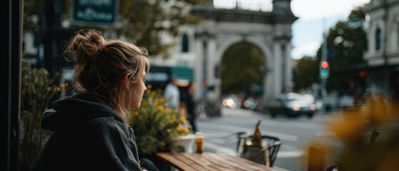 Obraz premium Thoughtful Caucasian woman sitting at outdoor cafe, contemplating life in urban setting with city arch background Concept of reflection, solitude, and urban lifestyle