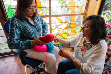 Cheerful Senior Women Sharing Crochet Tips in Cozy Living Room