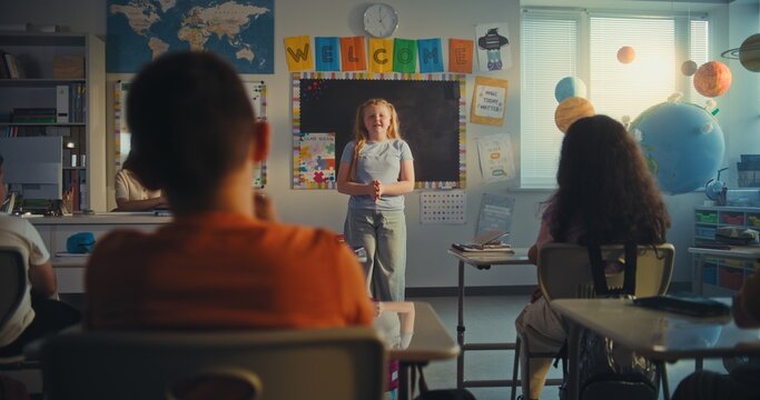 STEM Class on Renewable Energy: Female Teacher Educating Ecology to Diverse Elementary School Children. Talented Girl Talking, Presenting Homework in Front of Classroom Full of Classmates. Dolly Shot.