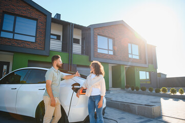 Couple charging electric car at home in sunny day