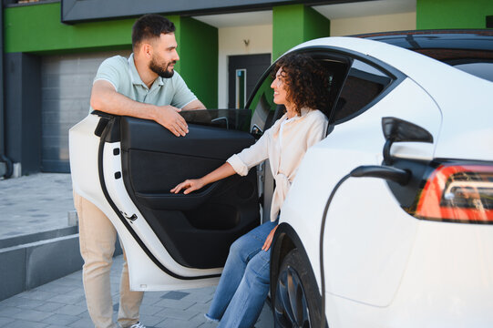 Couple charging electric car at home, embracing green energy and sustainable lifestyle - Powered by Adobe
