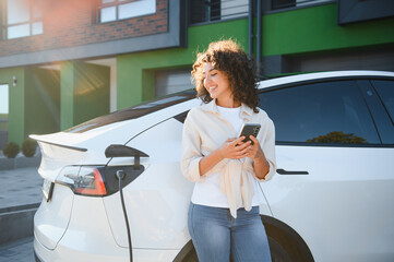 Young woman charging electric car at home