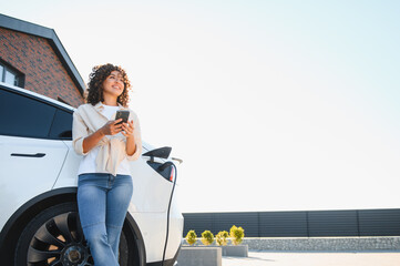 Young woman charging electric car at home