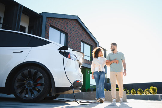 Couple walking near their electric car charging at home