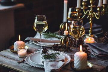 Rustic elegant table decor for christmas family dinner. Center piece with white candle, pine cone, fir tree branches. Zero waste eco-friendly home decoration. Cozy atmosphere, wooden background.