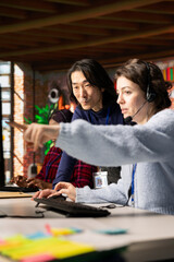 Fototapeta na wymiar Experienced call center onboarding specialist providing training to woman on how to use PC tools. Asian senior manager in customer support department office showing intern how to use company platforms