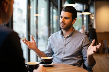 Man Explaining with Gestures at Cafe Table