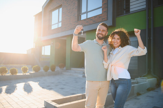 Happy couple showing keys to their new modern house