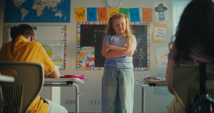 STEM Class on Renewable Energy: Elementary School Girl Presenting Homework on Ecology in Front of Classmates and Teacher. Diverse Children Sitting During Science Lesson in Classroom. Slow Motion. - Powered by Adobe