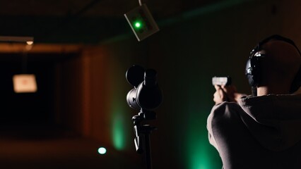 Shooting gallery client using rifle to hit targets, getting congratulated by instructor after great result. Woman doing thumbs up after receiving compliments for shooting bullseye, camera B