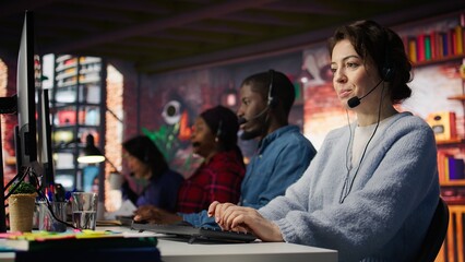 Customer support employees listening to clients issues. Teamworking call center agents in front of PC in office using headset mic to provide helpful solutions, solving customers concerns, camera B
