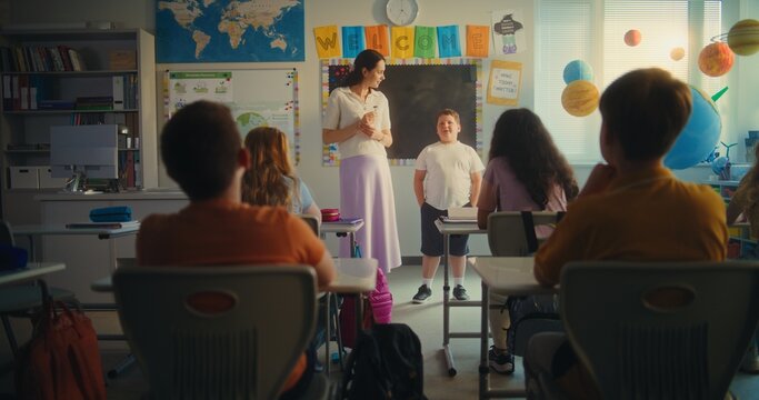 STEM Class on Renewable Energy: Elementary School Student Speaking about Energy Sources in Front of Classroom Full of Classmates and Teacher. Diverse Children Studying Ecology and Science. Slow Motion - Powered by Adobe