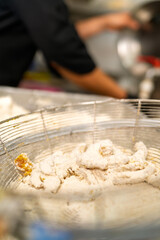 Chef preparing fish in flour for frying in restaurant kitchen