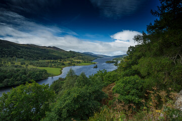 Serene landscape view of a river winding through lush green hills under a bright blue sky