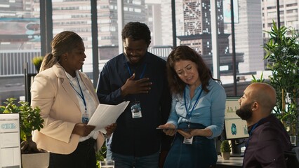 Employees and coworker with disability looking over revenue figures in inclusive office. Man in wheelchair working together with colleagues, comparing company statistical numbers, camera A