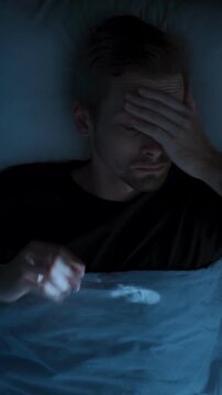 Top view, man restlessly sleeping in bed at night and waking up abruptly with a startle. Insomnia sleep paralysis, sleep disorder. vertical video