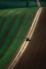 Fototapeta premium Tractor on Rural Dirt Road, Hillside Farmland, Agriculture