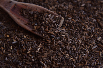 Erva-Mate, roasted mate herb for tea. Toasted Mate Tea and a wooden spoon. Traditional Brazilian beverage. Close-up