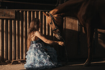 Title: Delicate interaction of a woman in an airy dress with a horse in a stable, warm light creates an atmospheric scene full of peace and closeness