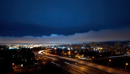 Fototapeta premium Night highway traffic, city lights, low clouds, aerial view, urban landscape