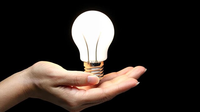 Illumination of Inspiration: A bright light bulb, symbol of innovation, creativity, and ideas, held in the gentle palm of a hand, set against a dark backdrop.