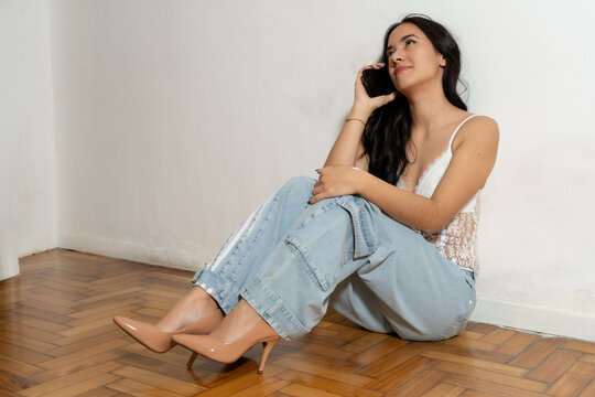 Young latin woman talking on phone and smiling, reflecting on conversation
