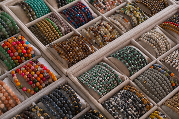 Handcrafted bracelets of various designs and colors are neatly arranged in trays