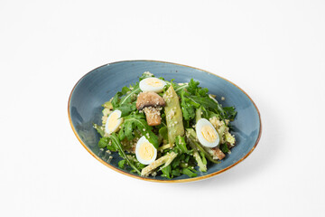 Quinoa salad with arugula, mushrooms, snow peas, avocado, and quail eggs on a plate. White background